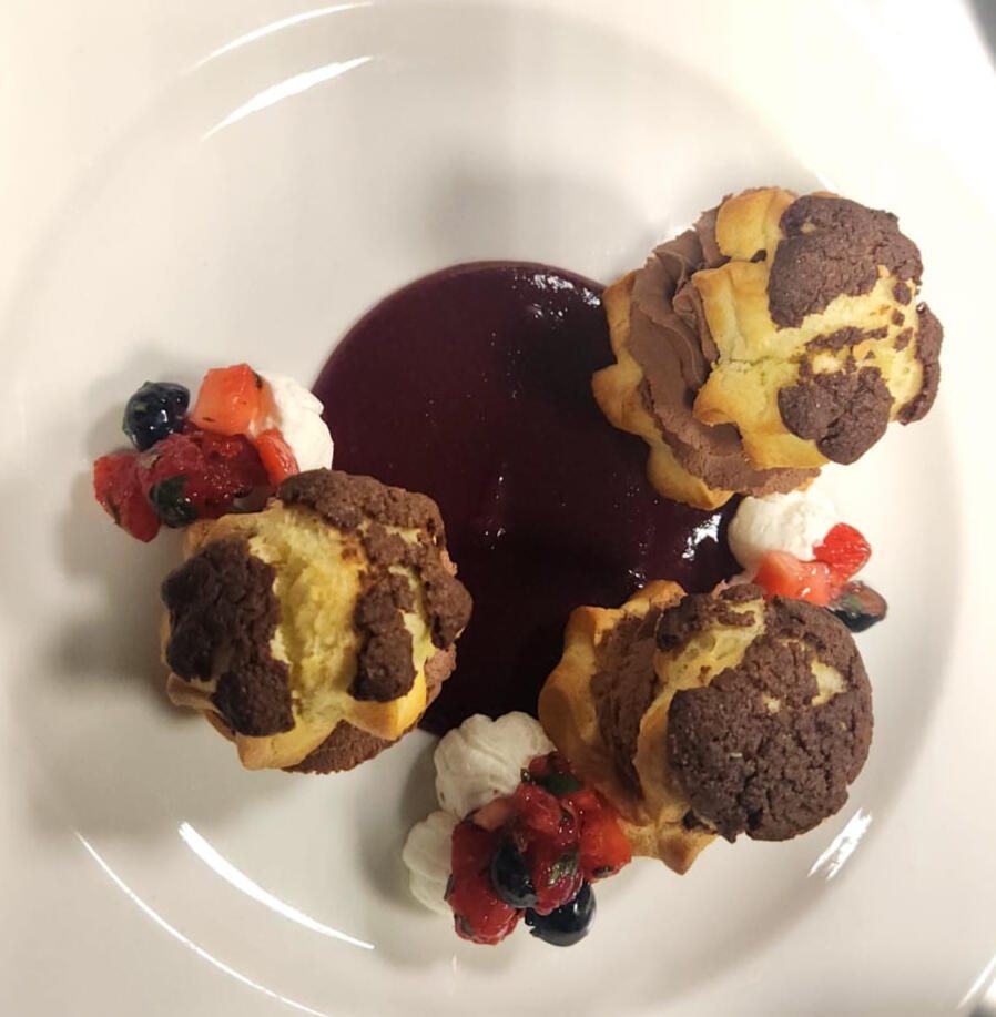 Custard eclairs with berries and chocolate sauce